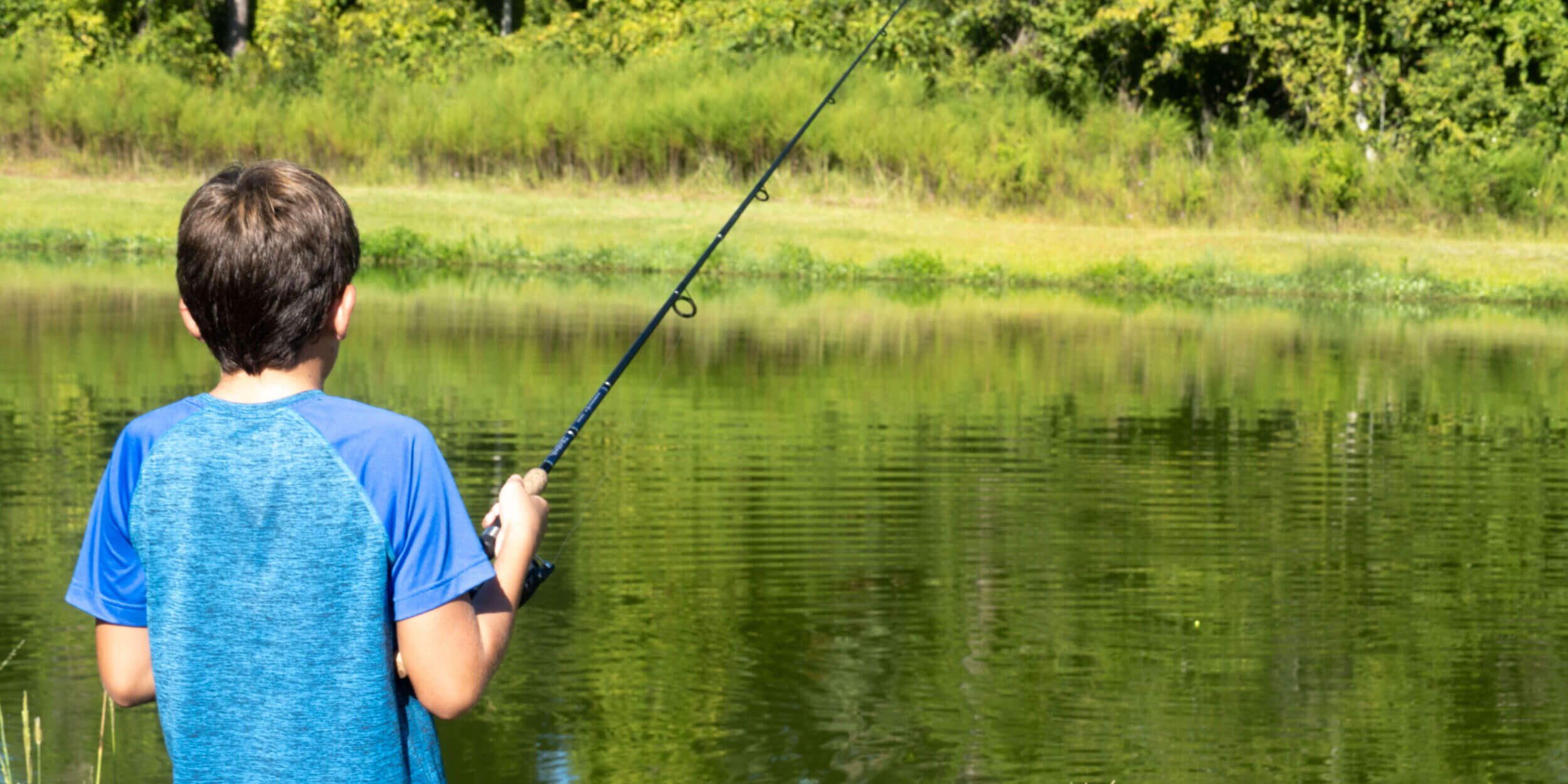 Boy fishing from shore in Blue Shirt with Pole_Putnam County_Brandy Jo Hastings_ Boy fishing from shore in Blue Shirt with Pole_Putnam County_Brandy Jo Hastings_